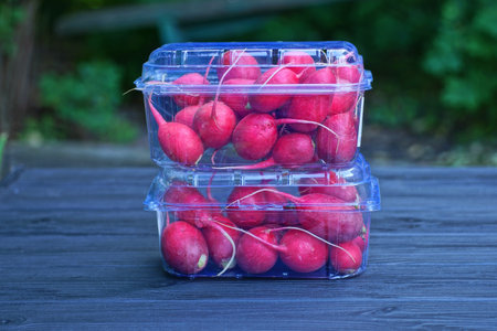 Fresh red radishes in plastic box on wooden table, selective focusの写真素材