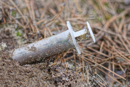 old plastic syringe on the ground in the forest, environmental pollution