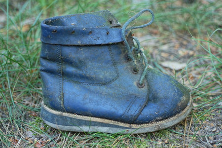 one old little blue leather boot stands on the ground on the street