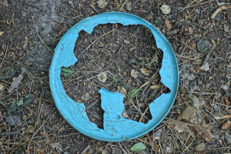 one big broken blue round cap with a hole lies on the gray ground on the streetの写真素材