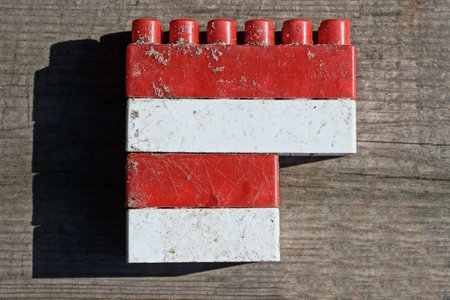red white small plastic cube brick toy lies on a gray wooden tableの写真素材