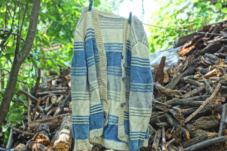 one crumpled knitted woolen white blue sweater hanging on a wire on the streetの写真素材