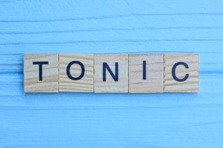 word tonic made of small gray wooden letters on a blue wood backgroundの写真素材