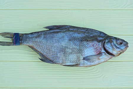 food from one gray dry salted fish roach lies on a yellow wooden tableの写真素材