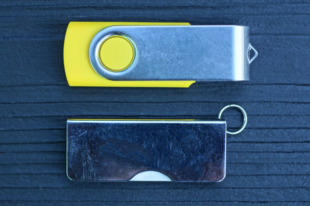 two small gray yellow closed mobile flash drive lie on a black wooden table