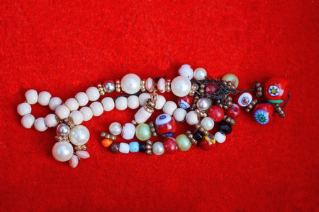 colorful pearl and bead necklace lie on red tableの写真素材