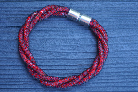 one red plastic bracelet made of wire lies on a black wooden table