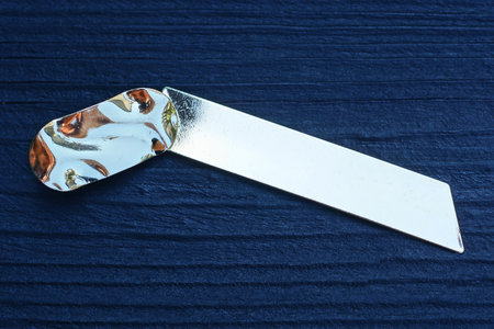 one yellow long gold earring lies on a black wooden table