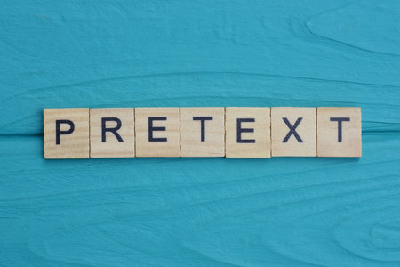 word pretext from small gray wooden letters lies on a blue background