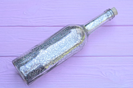 one gray bottle lies on a pink wooden tableの写真素材