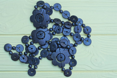 brown black plastic beads lie on yellow wooden tableの写真素材