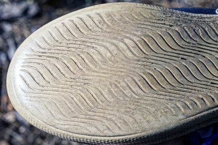 part of one gray dirty rubber sole shoe on the street