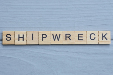 text the word shipwreck from wooden small letters with black font on an gray tableの写真素材