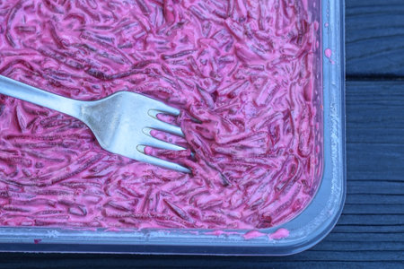 red beet salad with white mayonnaise in a plate with a metal fork stands on a black wooden tableの写真素材