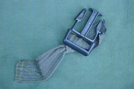 one black open plastic snap hook on a green harness on a backpack fabricの写真素材