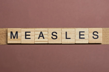 gray word measles made of wooden square letters on brown background
