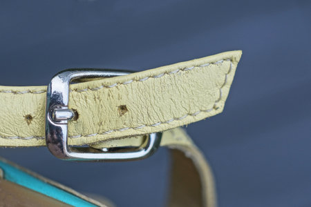 one closed gray metal clasp on a yellow leather sandal harnessの写真素材