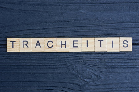 gray word tracheitis from small wooden letters on a black tableの写真素材