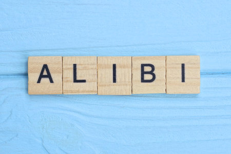 word alibi made from wooden gray letters lies on a blue backgroundの写真素材