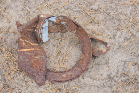 one piece of old rusty brown iron tin can lies on gray sand on summer streetの写真素材