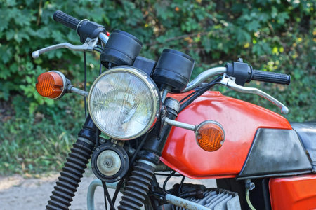 one old motorcycle with headlight and black handlebars on a summer streetの写真素材