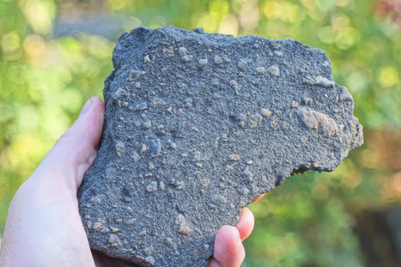 hand holding one large piece of black gray asphalt