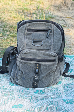 one big gray fabric backpack stands on a blanket on the ground on a summer streetの写真素材