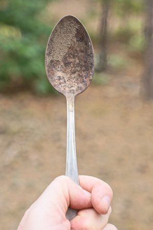 hand holding one old dirty metal spoonの写真素材