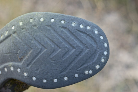 part of the boot with a rubber dirty old sole with a black pattern on a gray backgroundの写真素材
