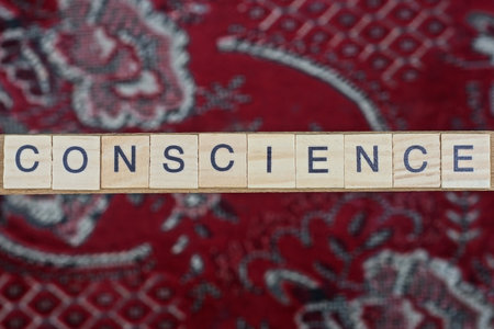 text the word conscience from gray wooden small letters with black font on a red tableの写真素材