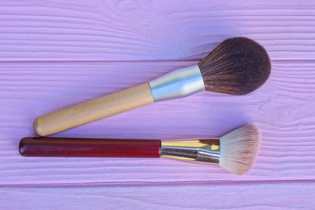 two red brown makeup brush lie on pink wooden tableの写真素材