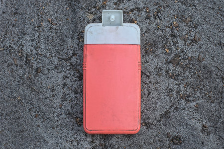 one old plastic red white bottle lies on the gray sandの写真素材