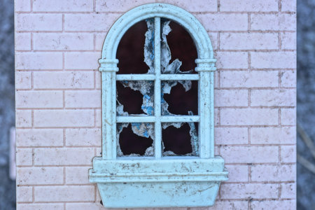 part of old single plastic toy house with broken white window on pink wallの写真素材