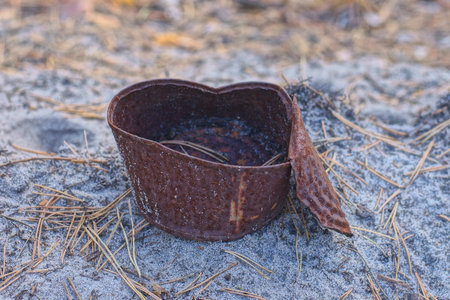 one old rusty brown iron can stand on the gray ground