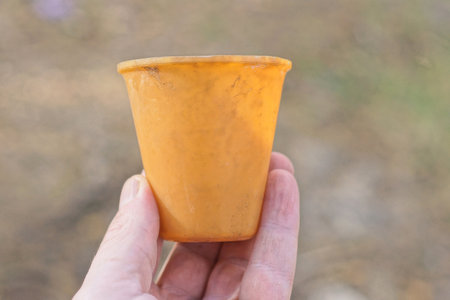 hand holding one plastic dirty old brown yellow on gray backgroundの写真素材