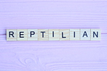 word reptilian from gray wooden small letters with black font on an pink backgroundの写真素材