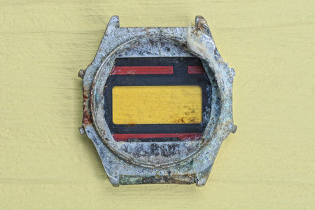 one old color metal case from a wristwatch lies on a yellow wooden table