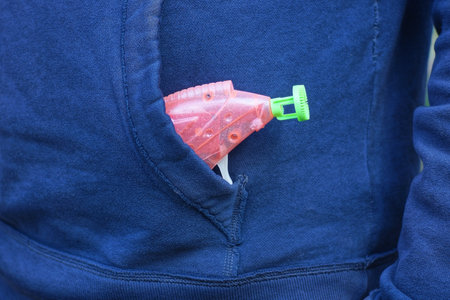 one pink plastic gun toy lies in the pocket of a blue jacketの写真素材