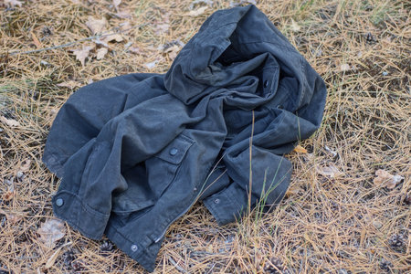 A black jacket lies on the ground in the forest. Autumn.の写真素材
