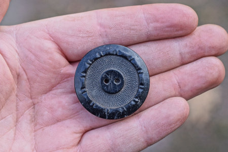 one big round plastic black button lies on the fingers of the handの写真素材