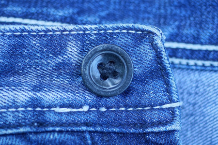 one large black plastic button on a blue fabric on jeans clothesの写真素材