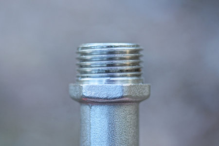 detail from a part of a white metal plumbing pipe with a thread on a gray background
