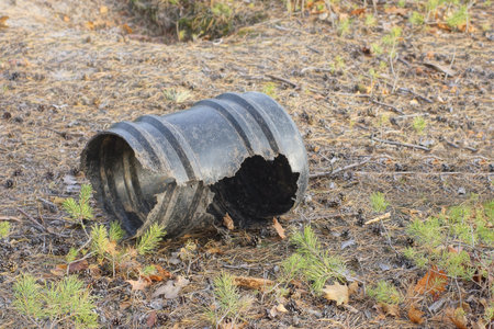 one big old broken black plastic barrel with a hole lies on the ground on the streetの写真素材