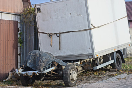 A truck with a broken trailer stands on the street near the houseの写真素材