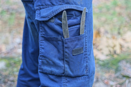 two gray iron knife in a mans blue pants pocket on his leg on the streetの写真素材