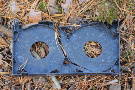 Broken old video cassette on the ground in the autumn forest.