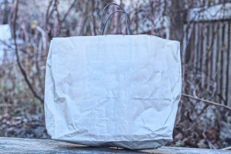 one white paper bag stands on a gray wooden tableの写真素材