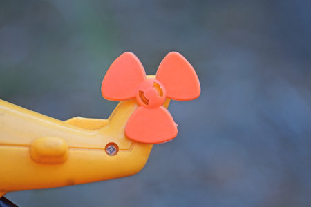 part of one yellow toy helicopter with orange blades on gray background