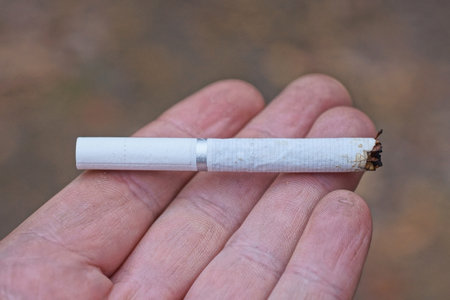 Close up of cigarette in hand on blurred background. Smoking concept.の写真素材