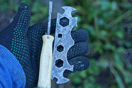 Hand in black glove holding a screwdriver and wrench